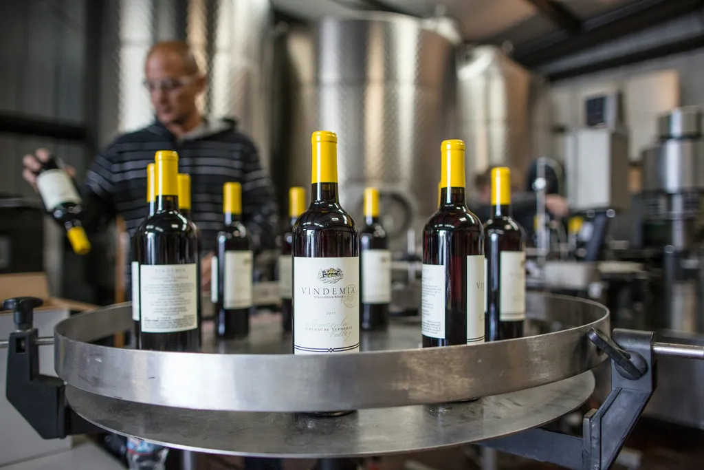 Finished bottles standing on a stainless steel table in a winery